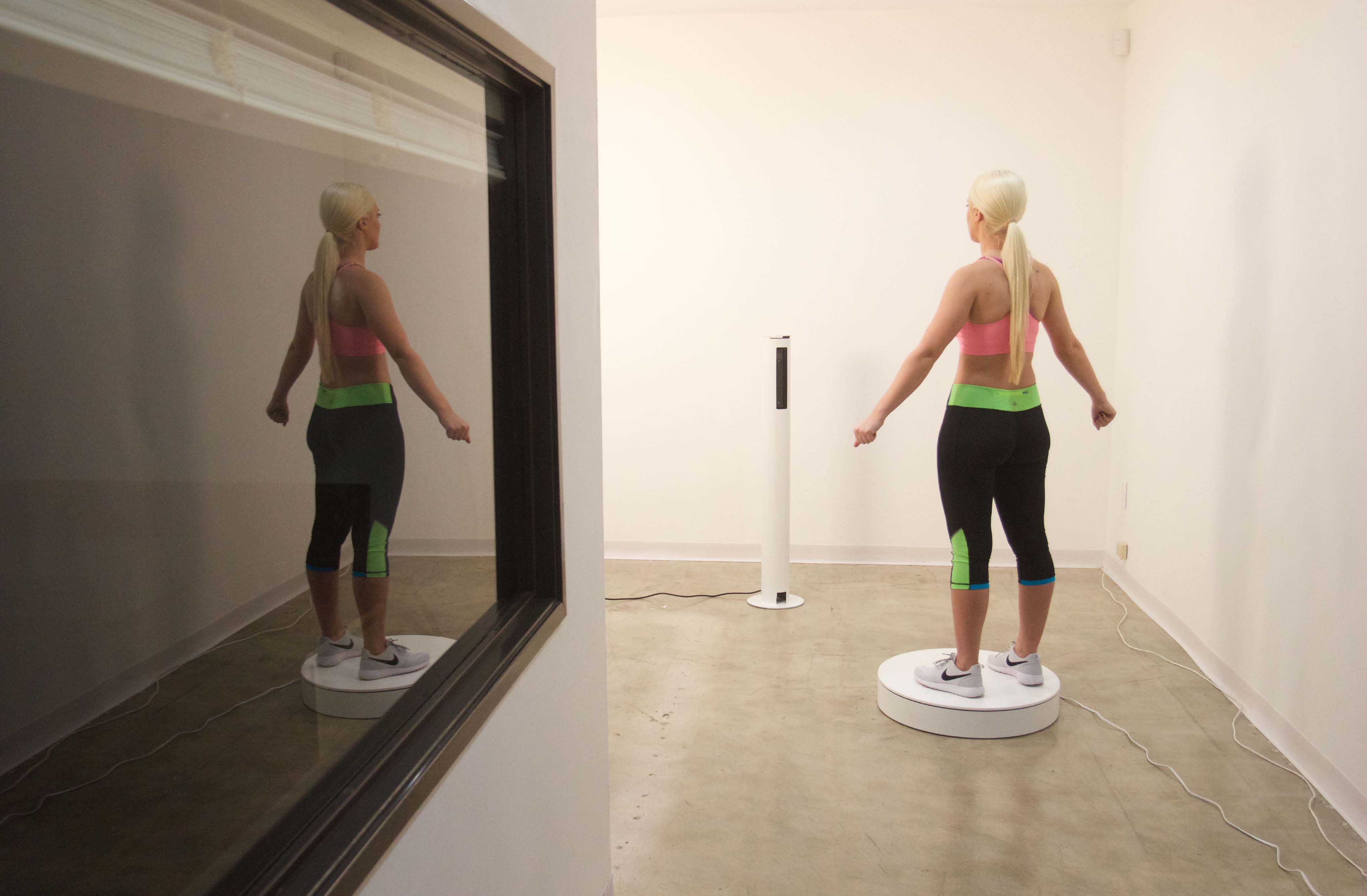 Woman doing barbell squats in front of a mirror with a personal trainer